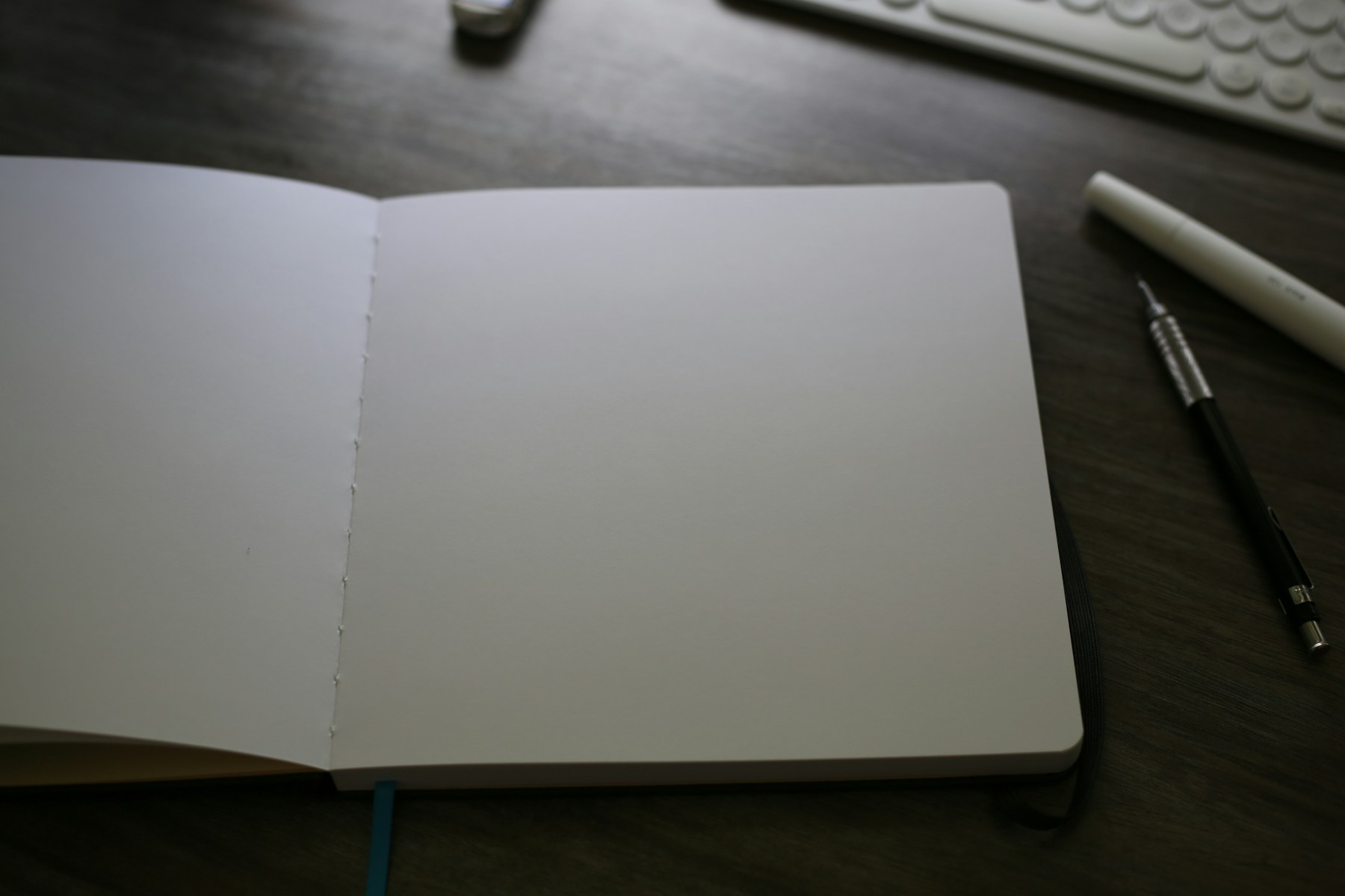 An open notebook sitting on a desk next to a keyboard