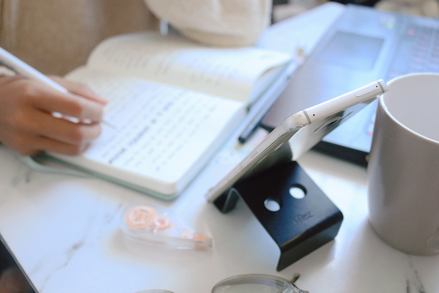 Hand writing in a notebook on a white desk