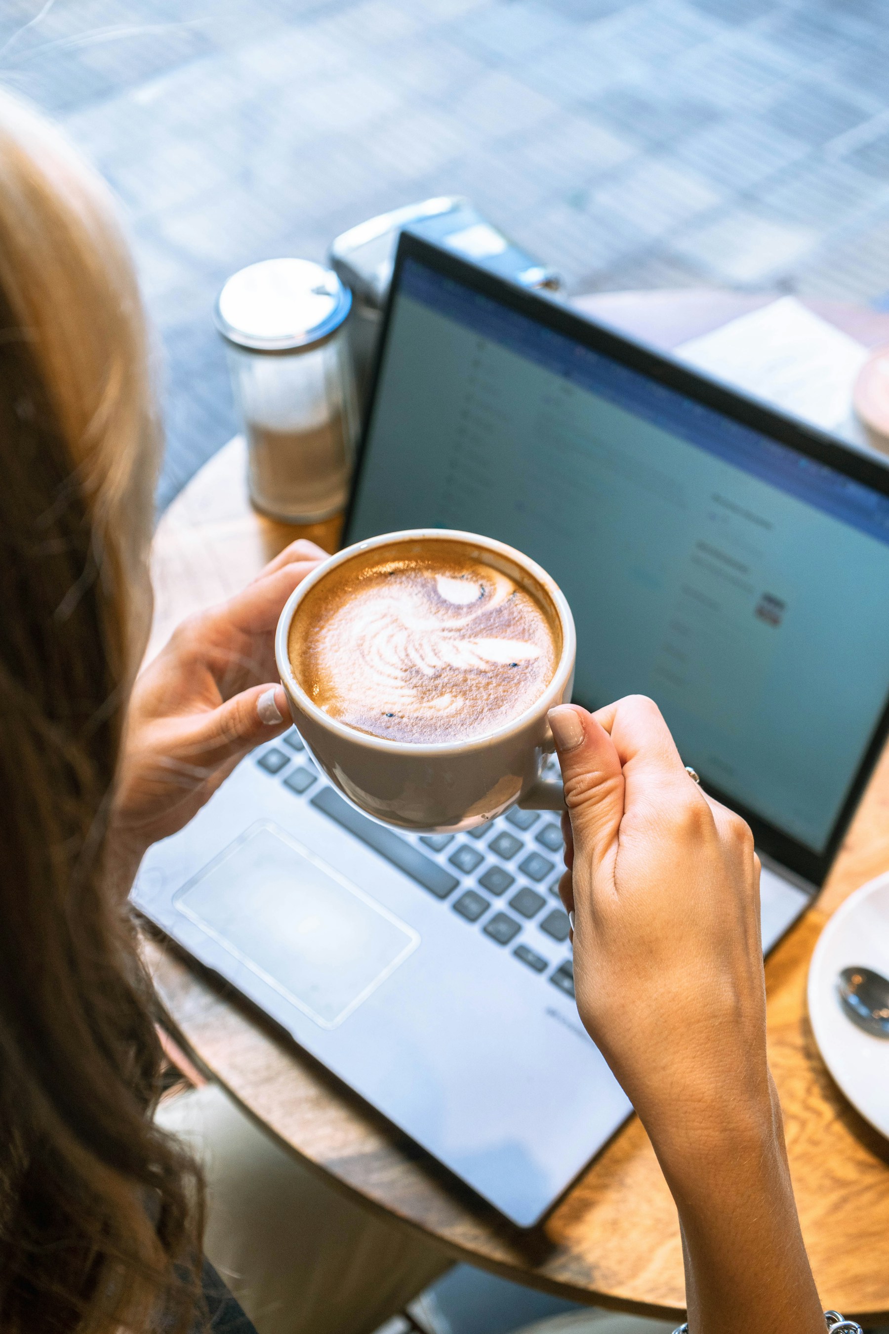 Woman enjoys coffee and laptop work at a cafe