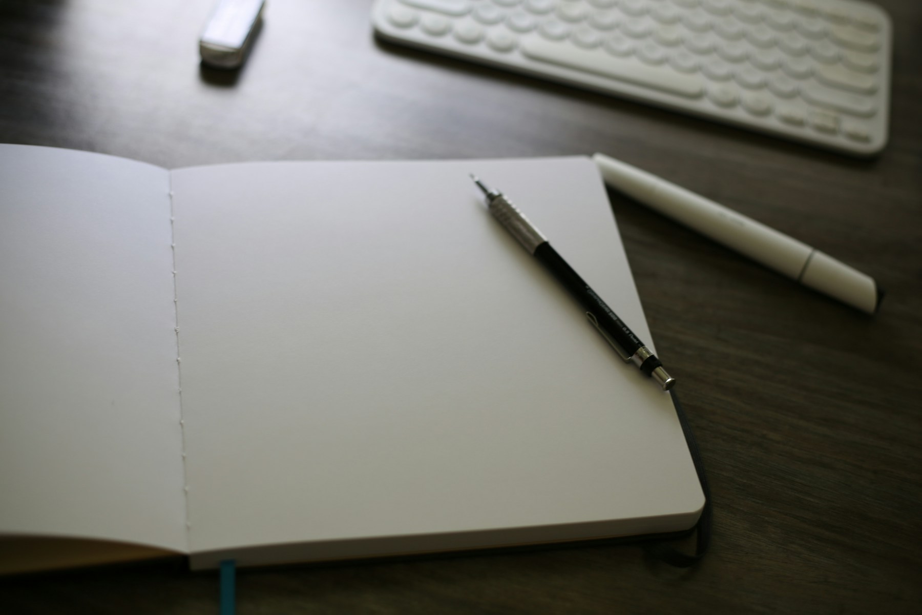 An open notebook sitting on top of a desk next to a keyboard